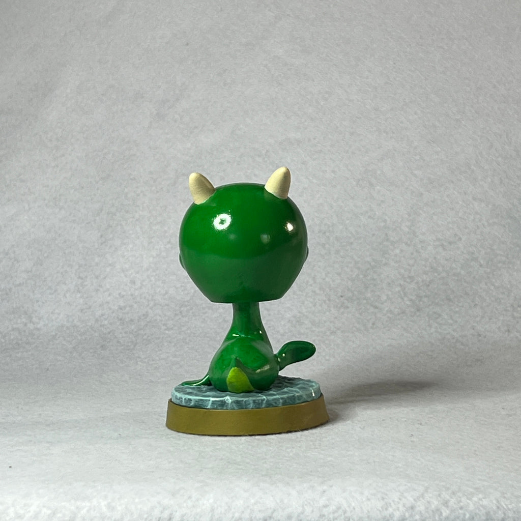 Green figurine with white accents on a textured gray background