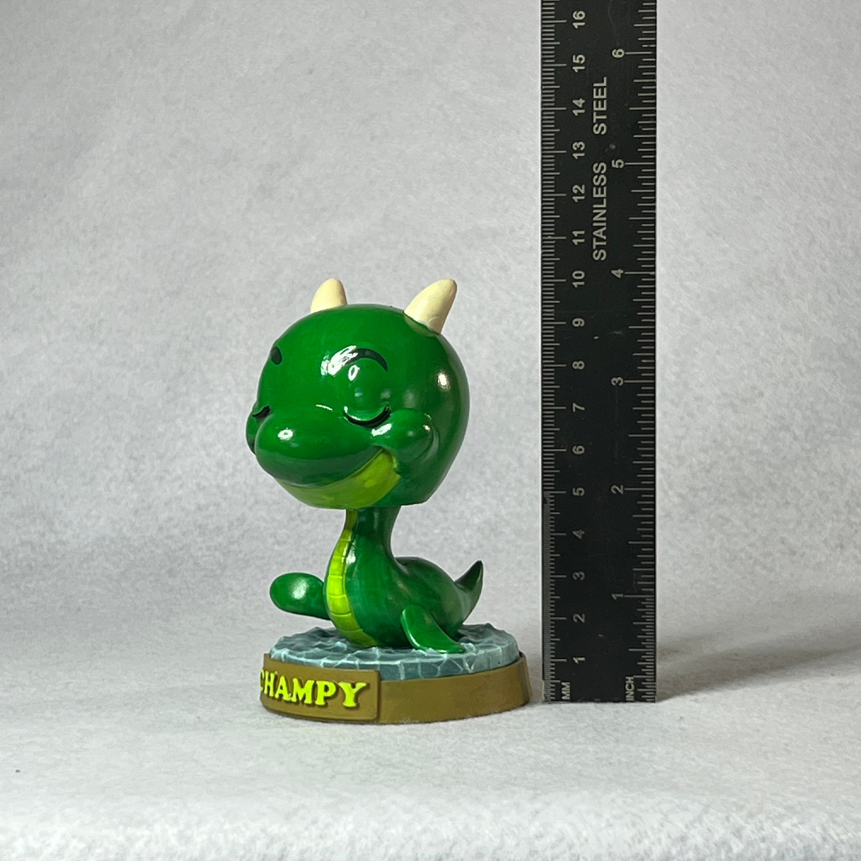 Green dragon figurine labeled 'Hampy' next to a ruler on a gray background