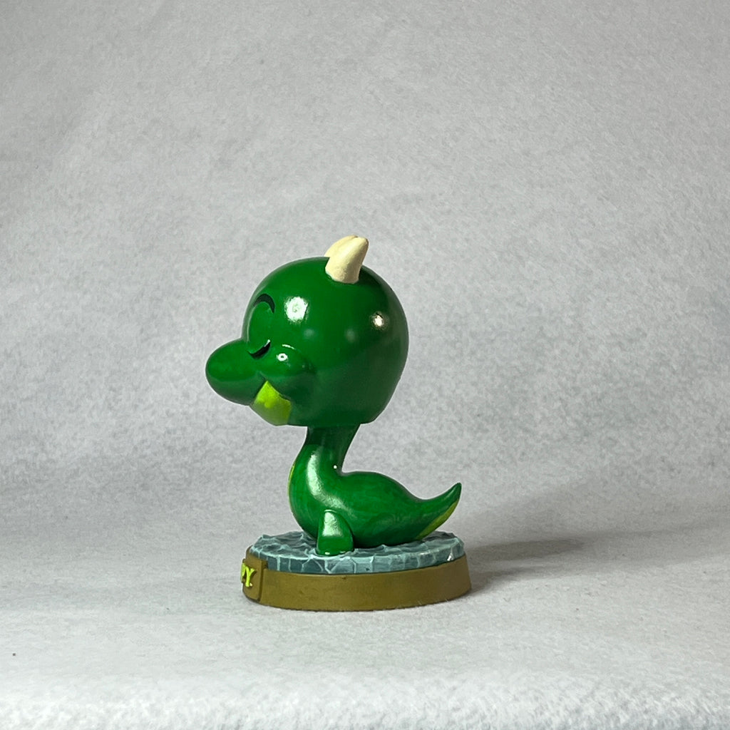 Green dinosaur figurine on a textured gray background