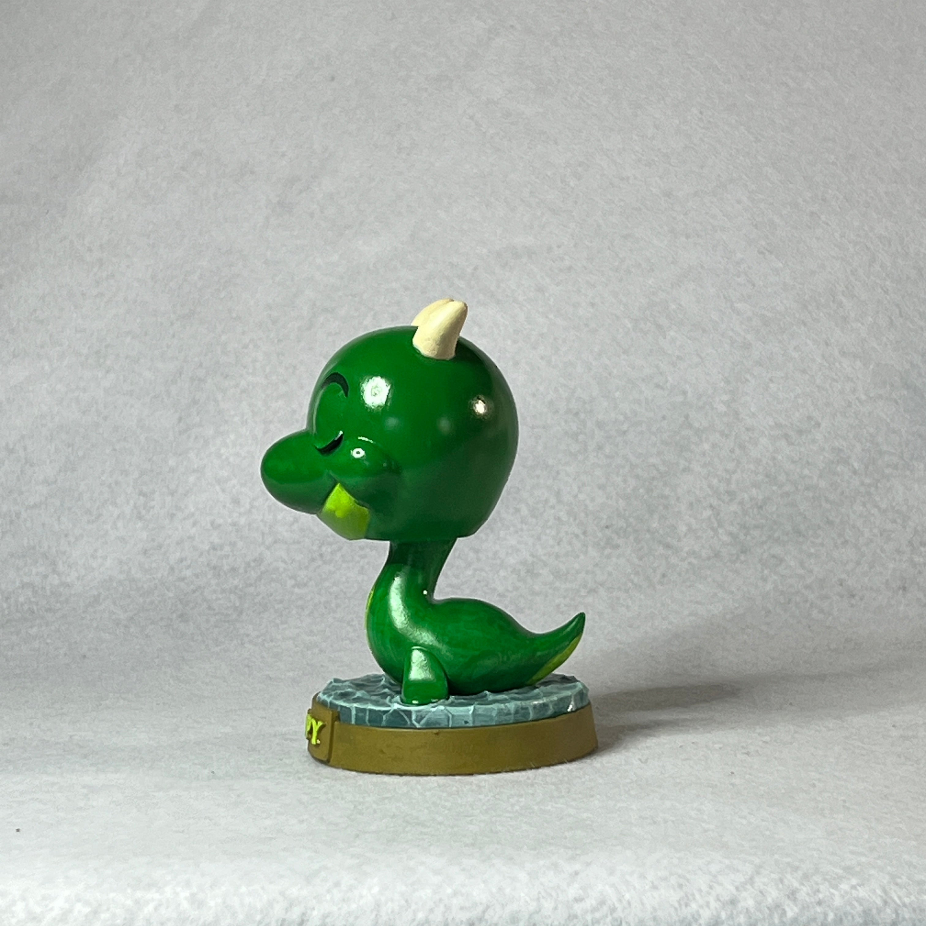 Green dinosaur figurine on a textured gray background