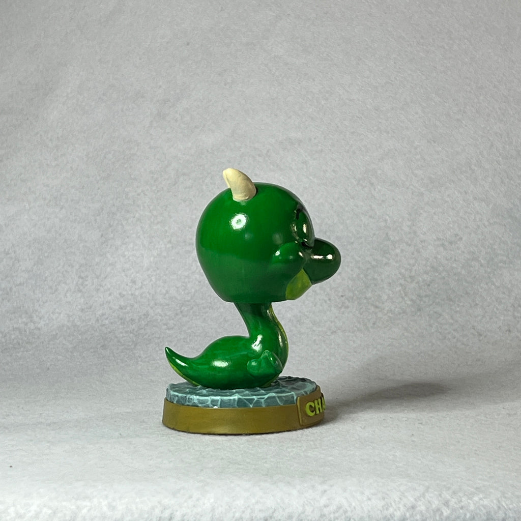 Green cartoon-like figure with a horn on a gray background