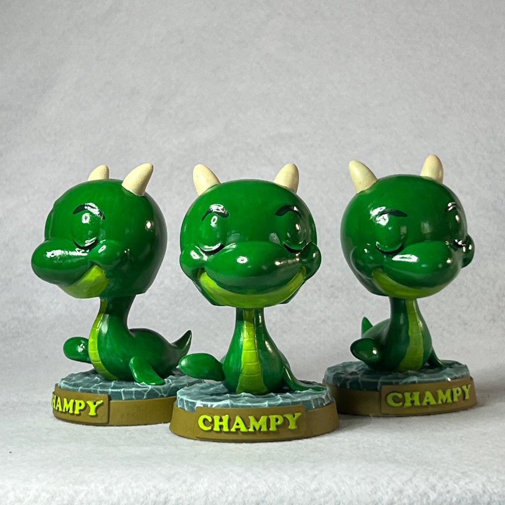 Three green dragon-like figurines with 'Champy' branding on a gray background