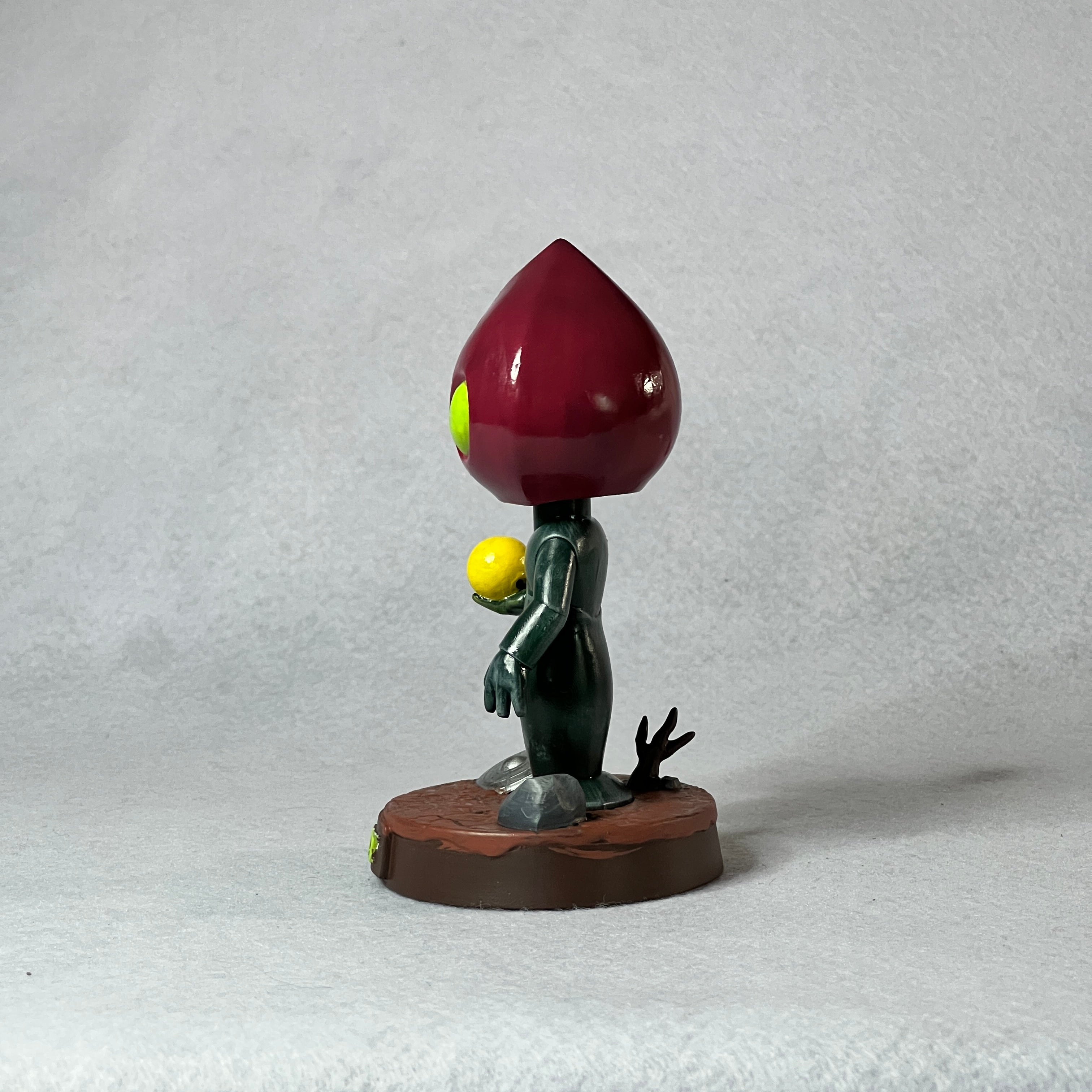 Small figurine of a character with a red cap and yellow body on a white background