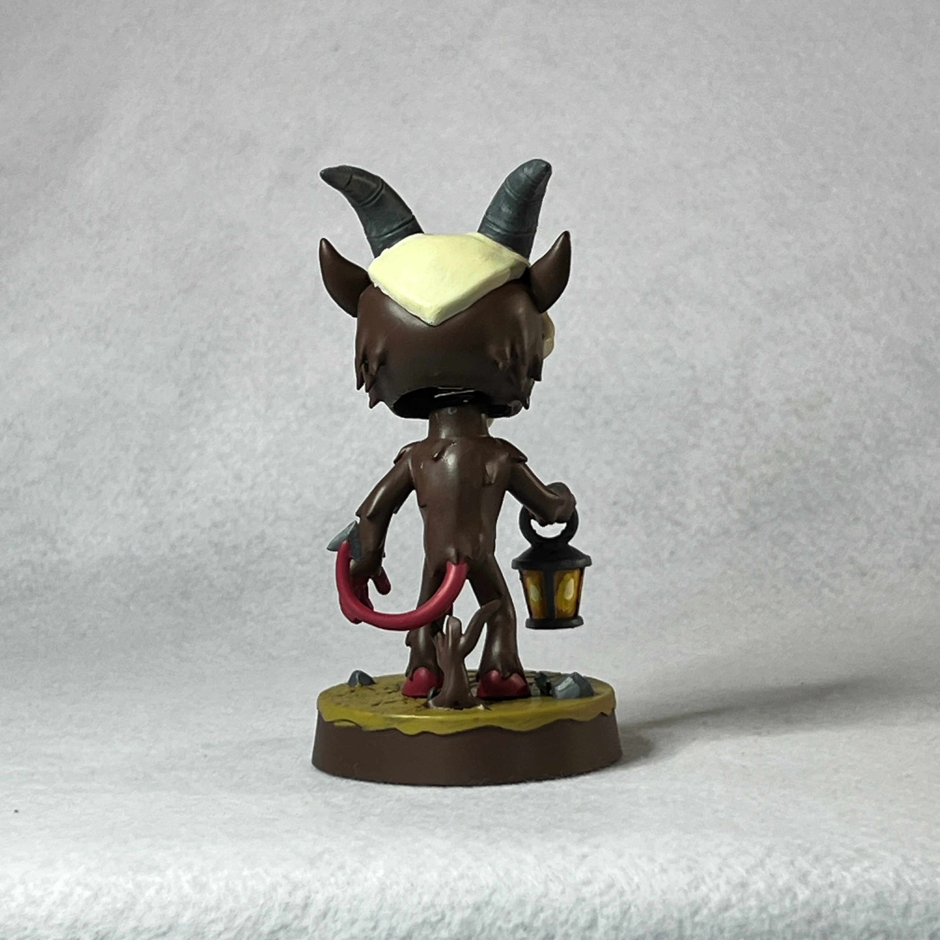 Figurine with horns and a lantern on a textured gray background