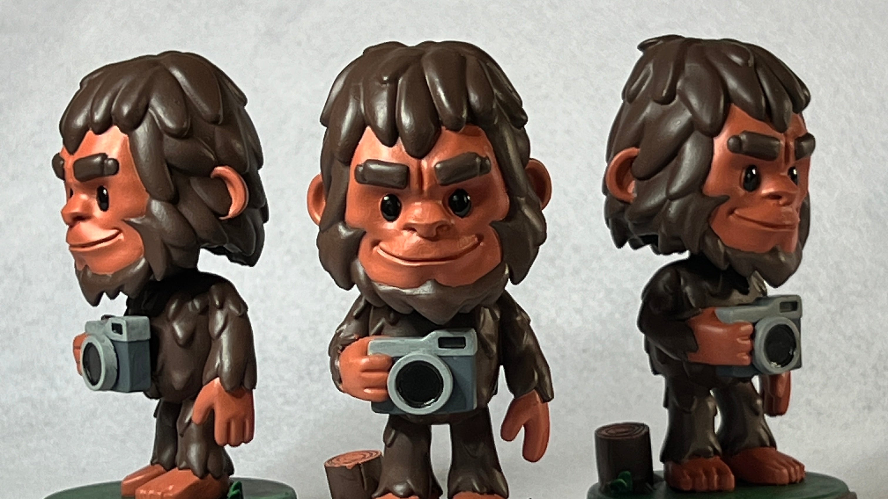 Three 'Stompz' figurines with camera props on a white background
