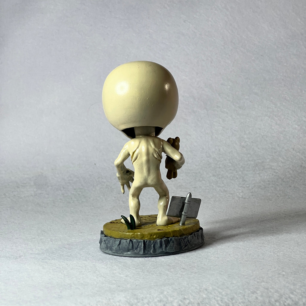 Small figurine with a large head on a gray background