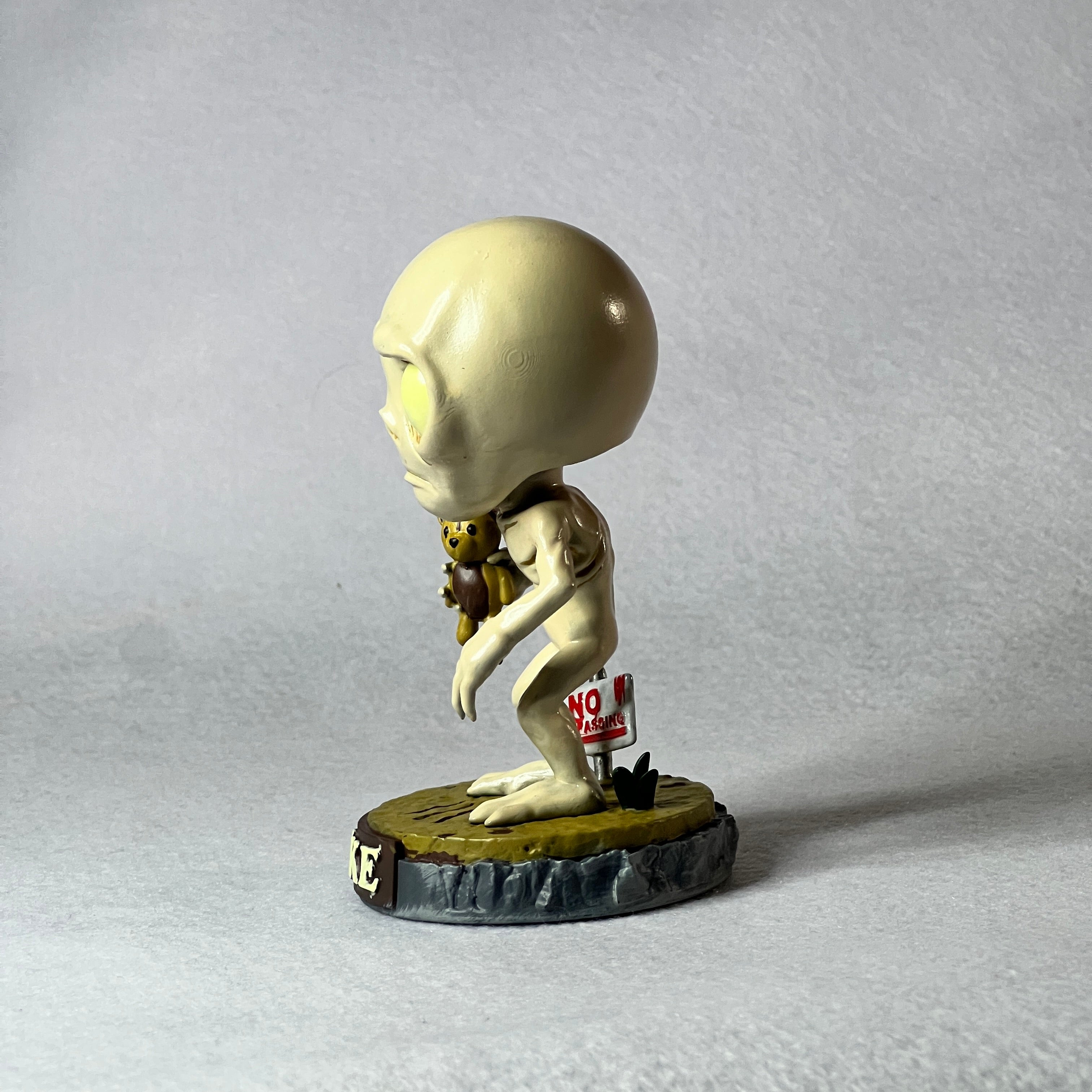 Small figurine of a humanoid with a round head on a gray background